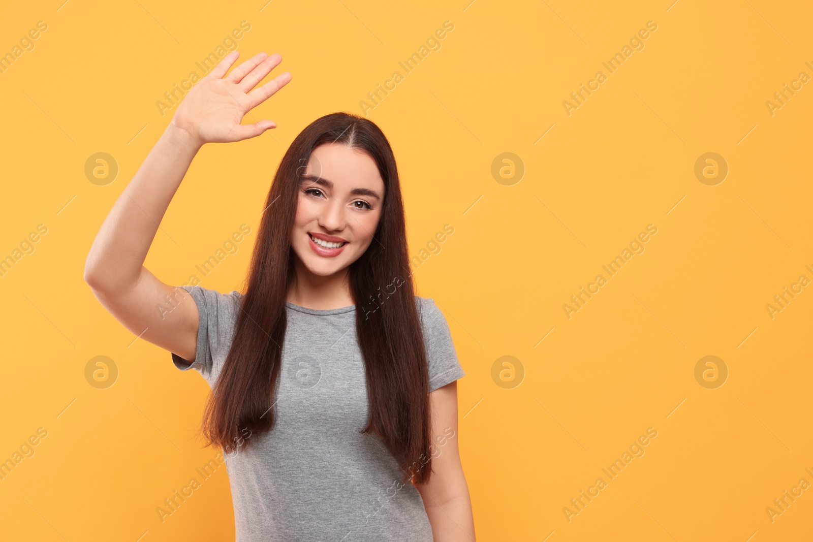 Photo of Happy woman giving high five on orange background, space for text