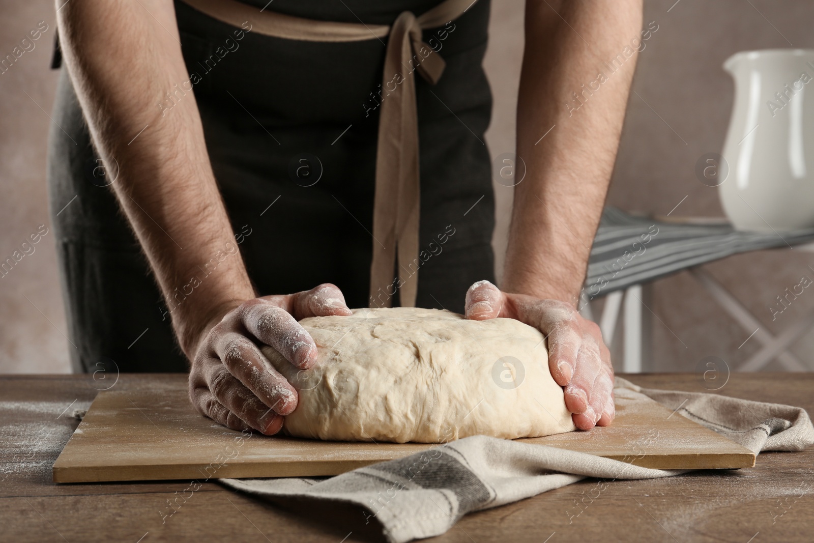 Photo of Male baker preparing bread dough at table, closeup