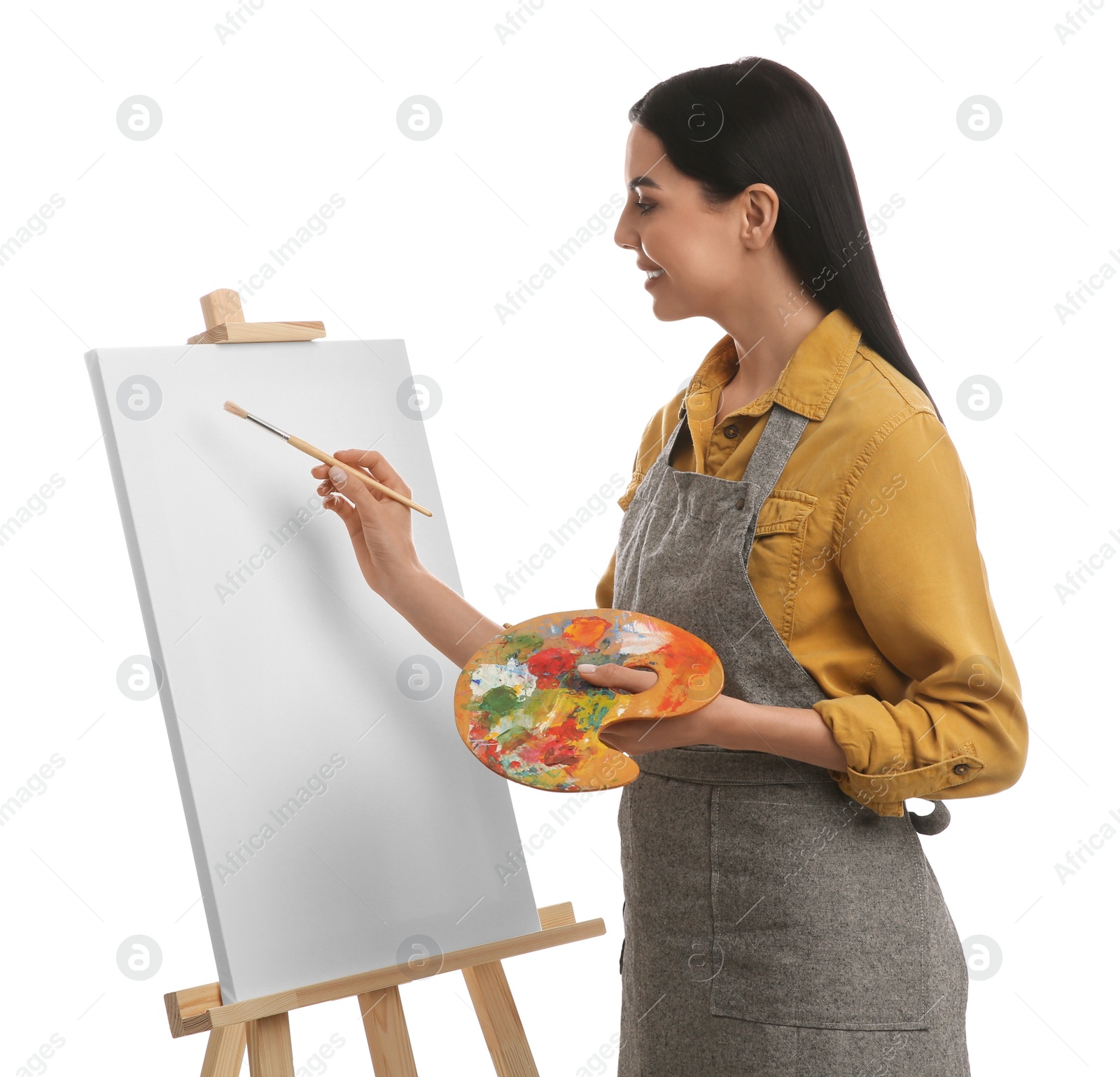 Photo of Young woman drawing on easel against white background