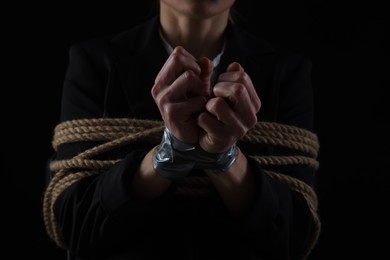Photo of Woman tied up and taken hostage on dark background, closeup