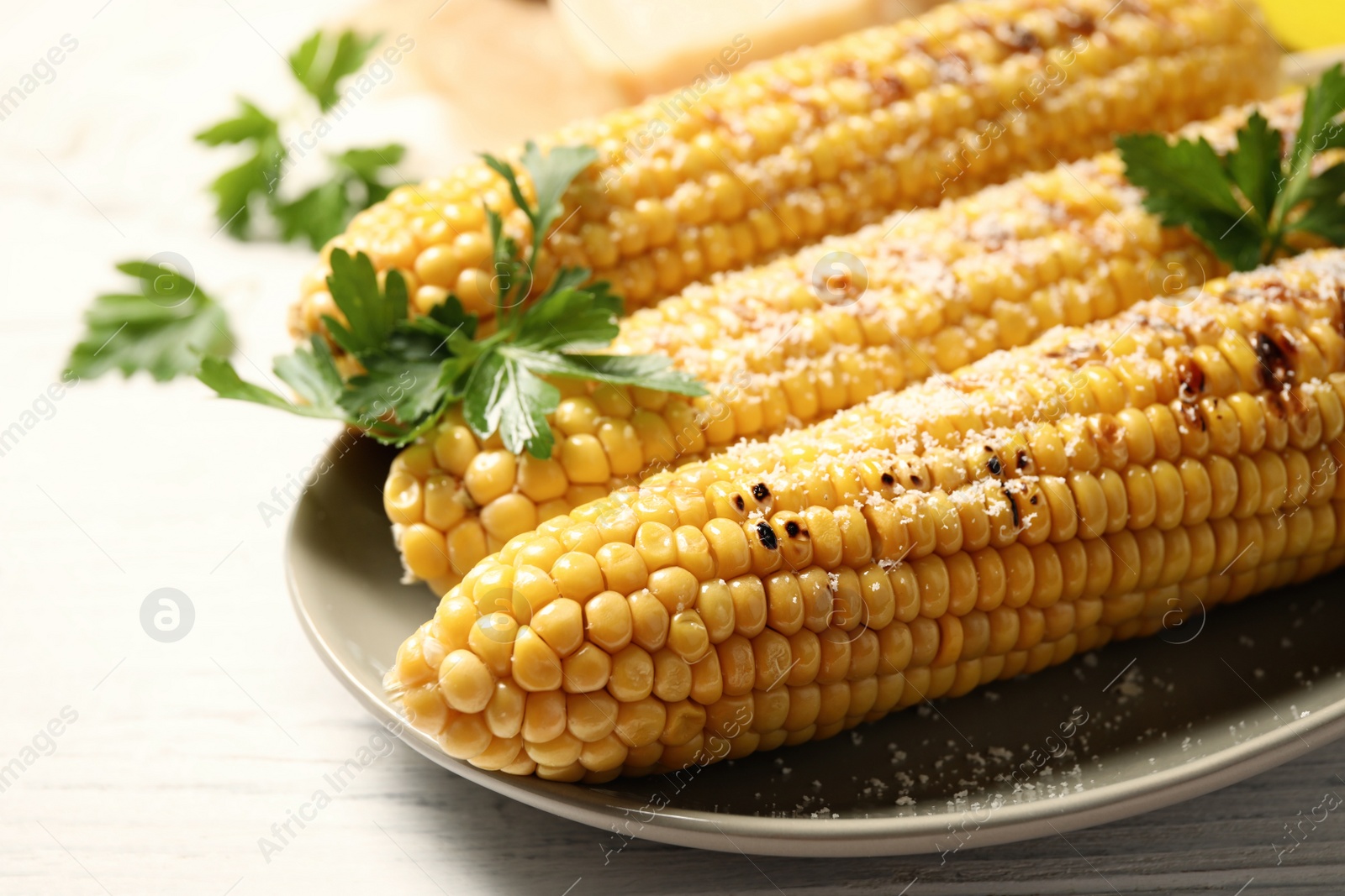 Photo of Tasty grilled corn on white wooden table