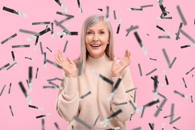 Happy woman and flying confetti on pink background