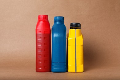 Photo of Motor oil in different canisters on light brown background