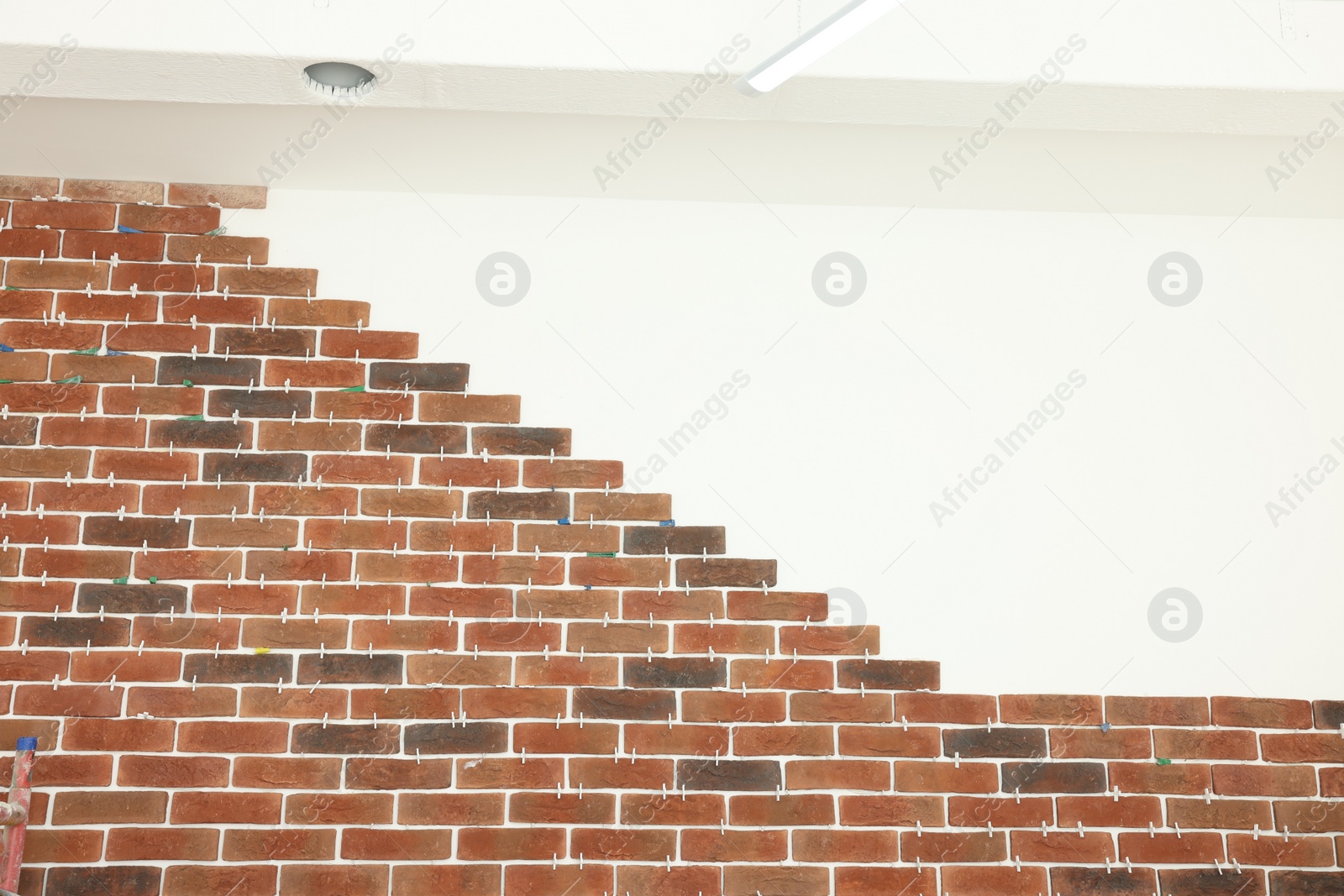 Photo of Decorative bricks with tile leveling system on white wall