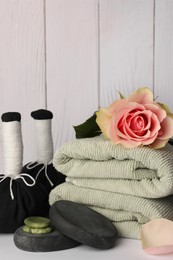 Photo of Composition with different spa products and rose on white table against wooden background
