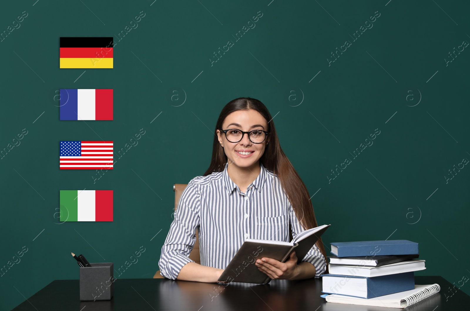 Image of Portrait of foreign languages teacher at wooden table and different flags green chalkboard