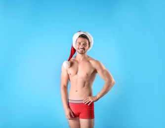 Photo of Shirtless young Santa Claus with sexy body on color background