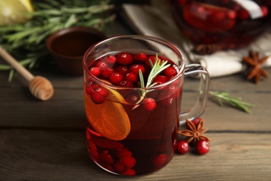 Photo of Tasty hot cranberry tea with rosemary and lemon on wooden table
