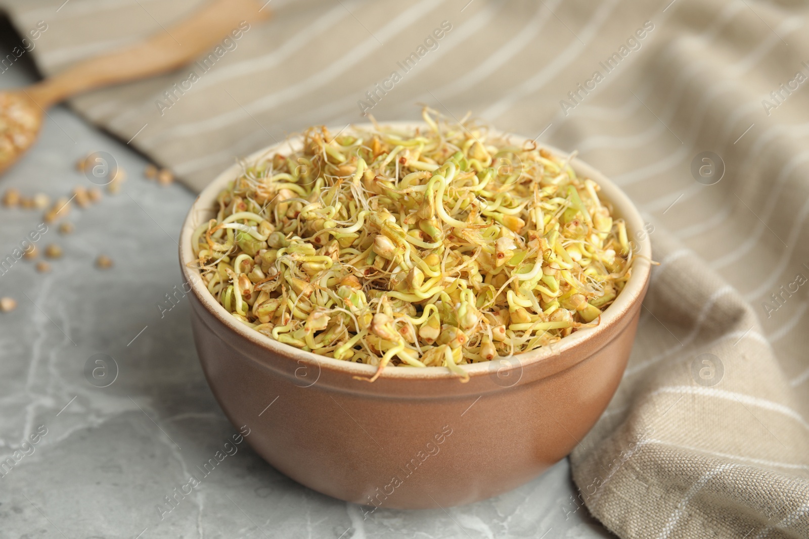 Photo of Bowl of sprouted green buckwheat on light grey table