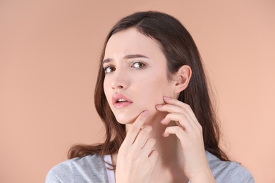 Teenage girl with acne problem against color background