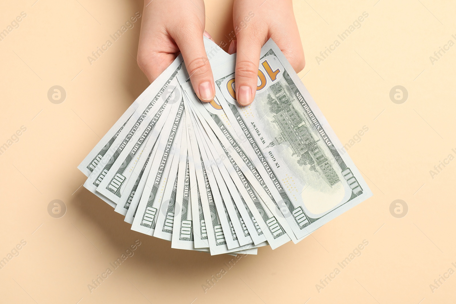 Photo of Money exchange. Woman holding dollar banknotes on beige background, top view