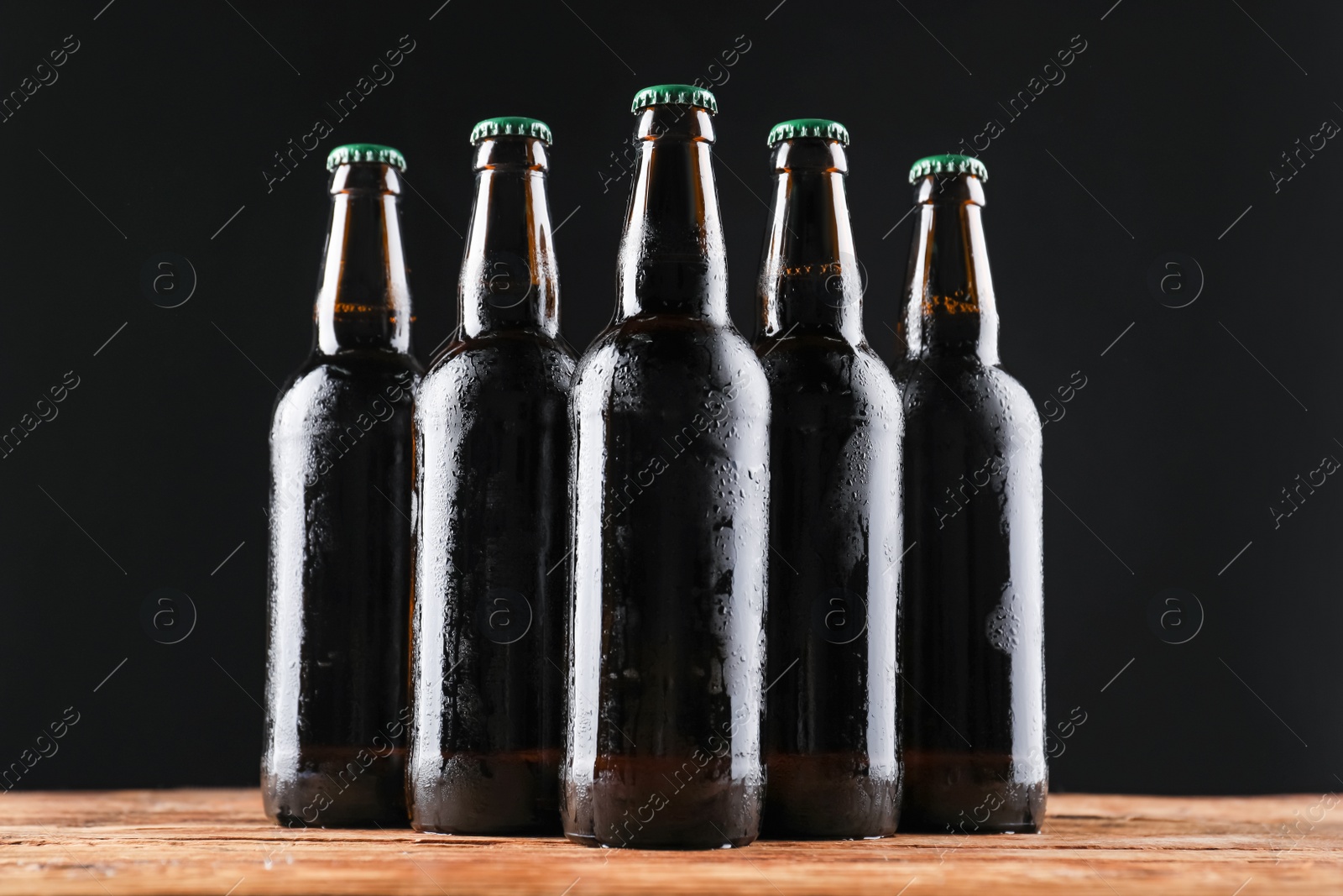 Photo of Many bottles of beer on wooden table against dark background