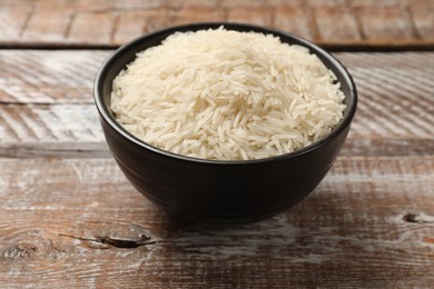 Photo of Raw basmati rice in bowl on wooden table