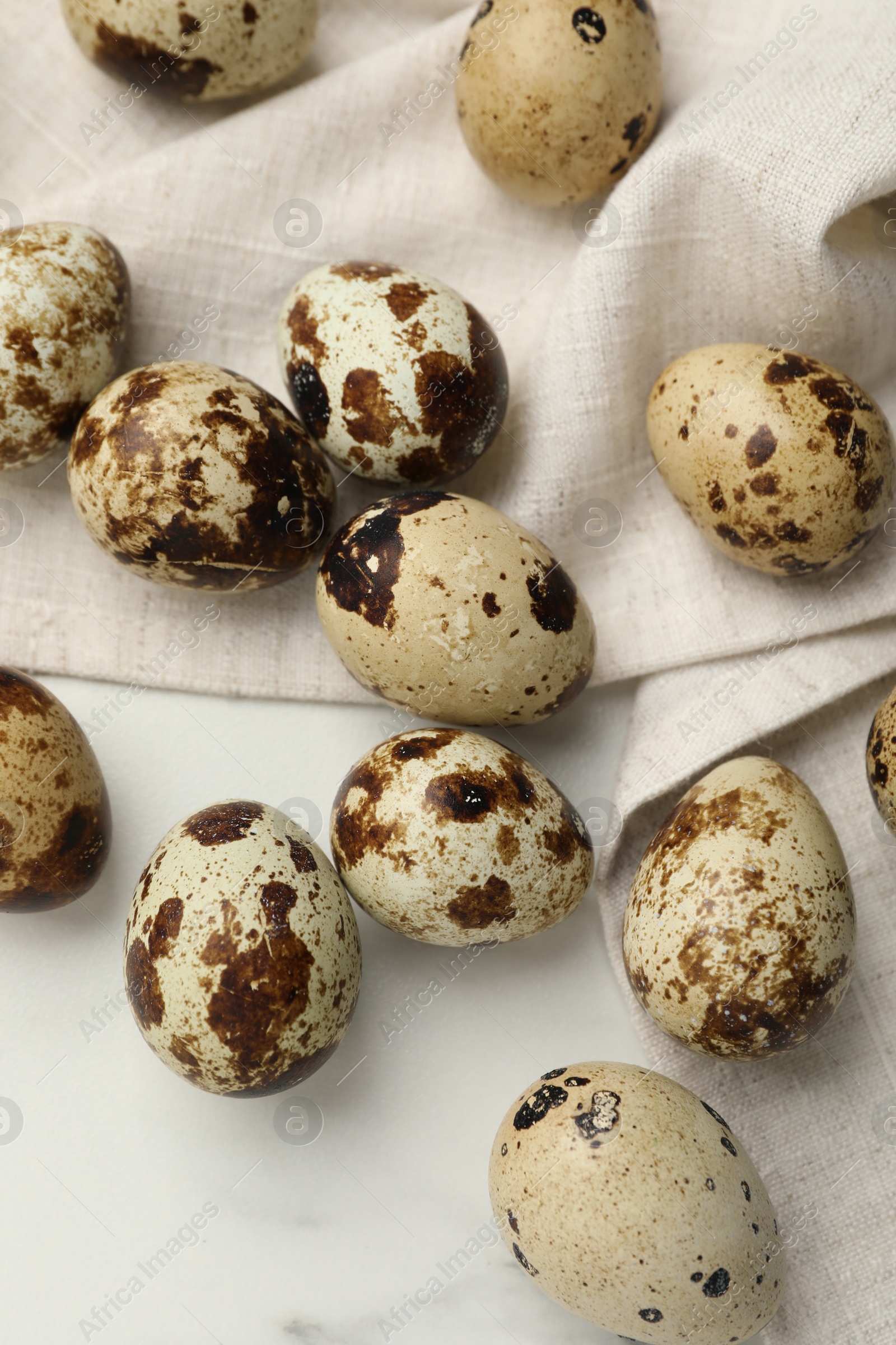 Photo of Many speckled quail eggs on white table, flat lay