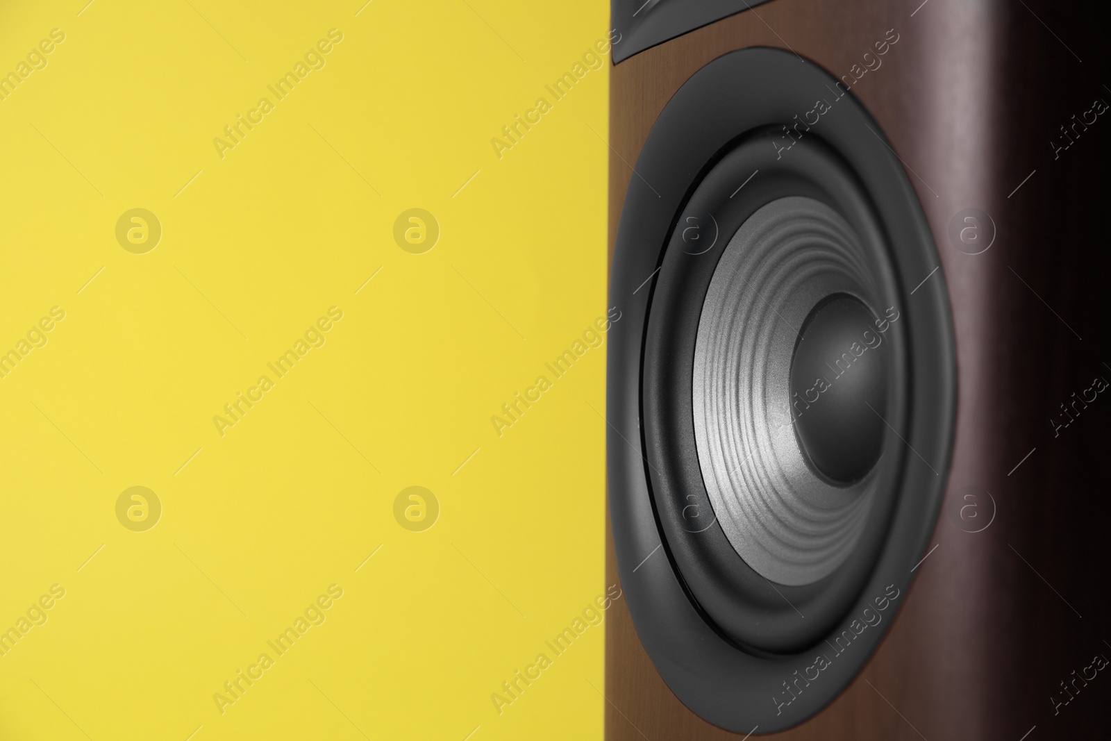 Photo of One wooden sound speaker on yellow background, closeup. Space for text