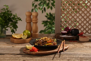 Photo of Stir-fry. Tasty noodles with meat and vegetables served on wooden table