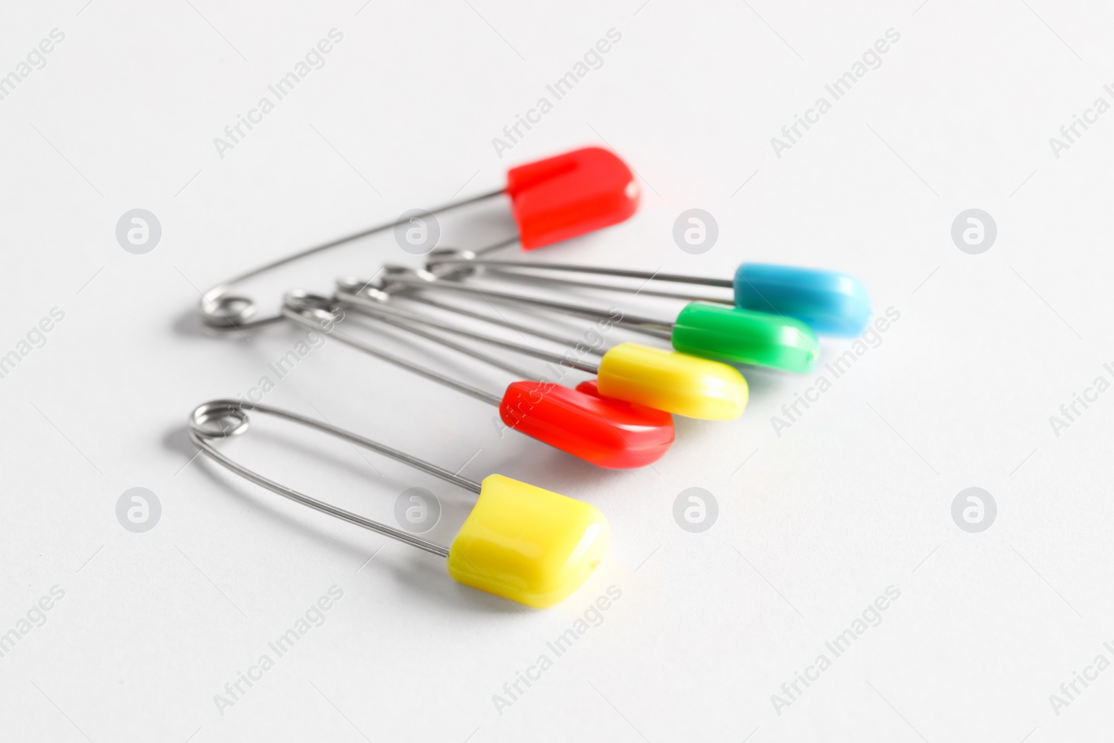 Photo of Colorful safety pins on white background, closeup