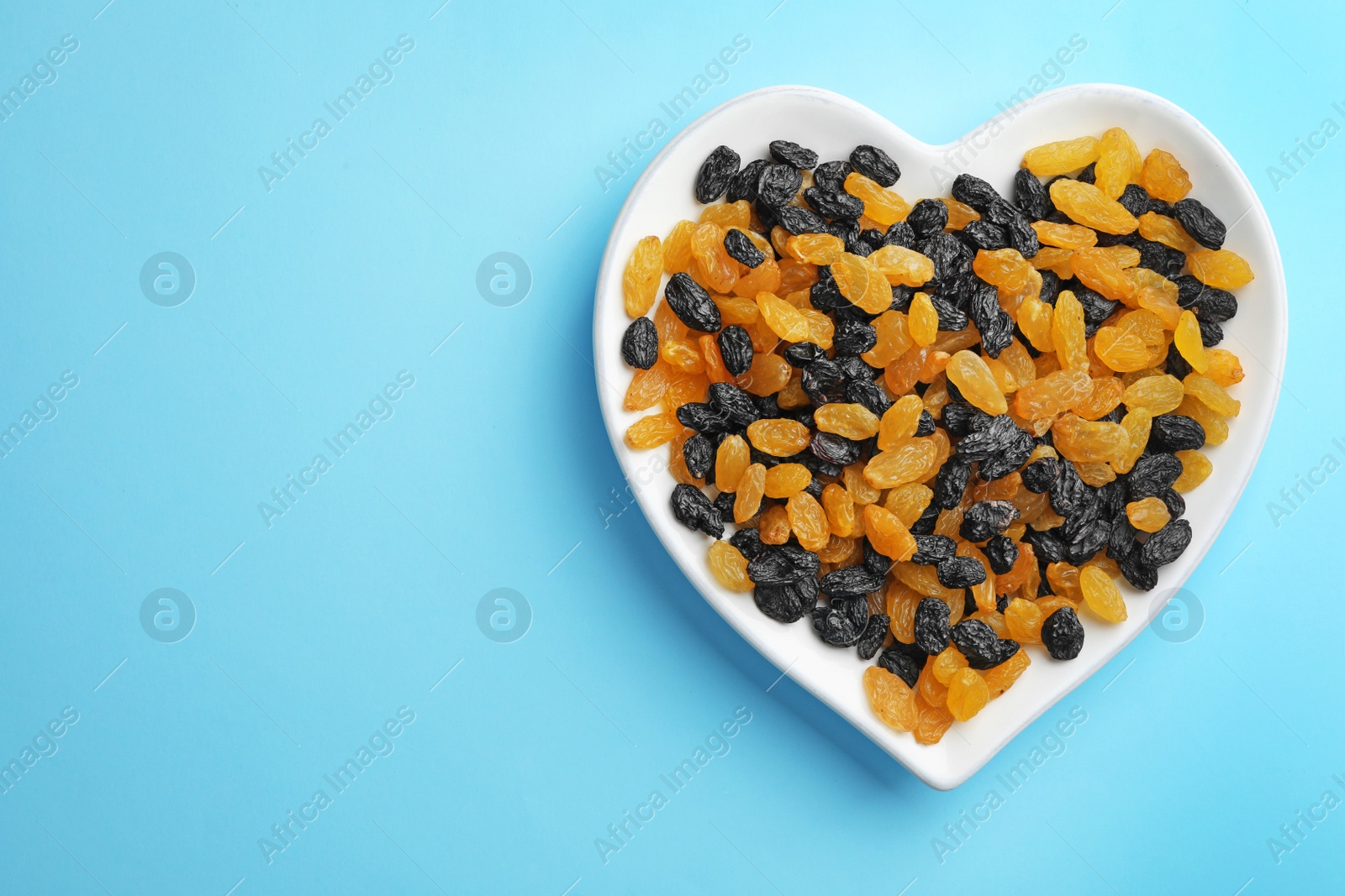 Photo of Plate of raisins on color background, top view with space for text. Dried fruit as healthy snack