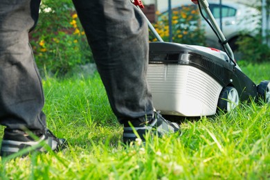 Man cutting grass with lawn mower in garden, closeup