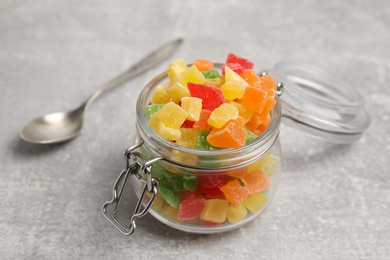 Mix of delicious candied fruits in jar on light grey table