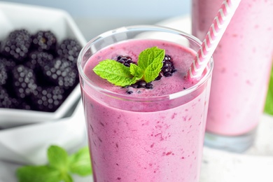 Photo of Delicious blackberry smoothie in glass on light table, closeup