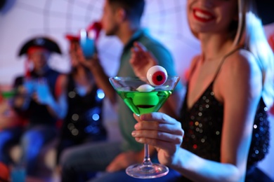 Photo of Woman holding cocktail with jelly eyeballs at Halloween party, closeup