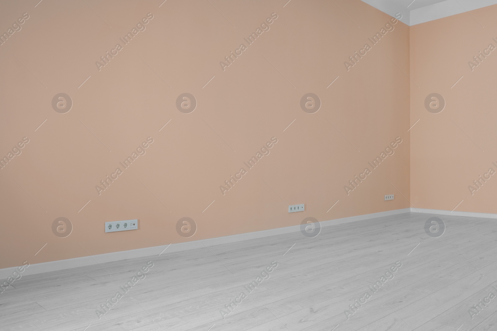 Photo of Pale orange walls with power outlet sockets in empty room