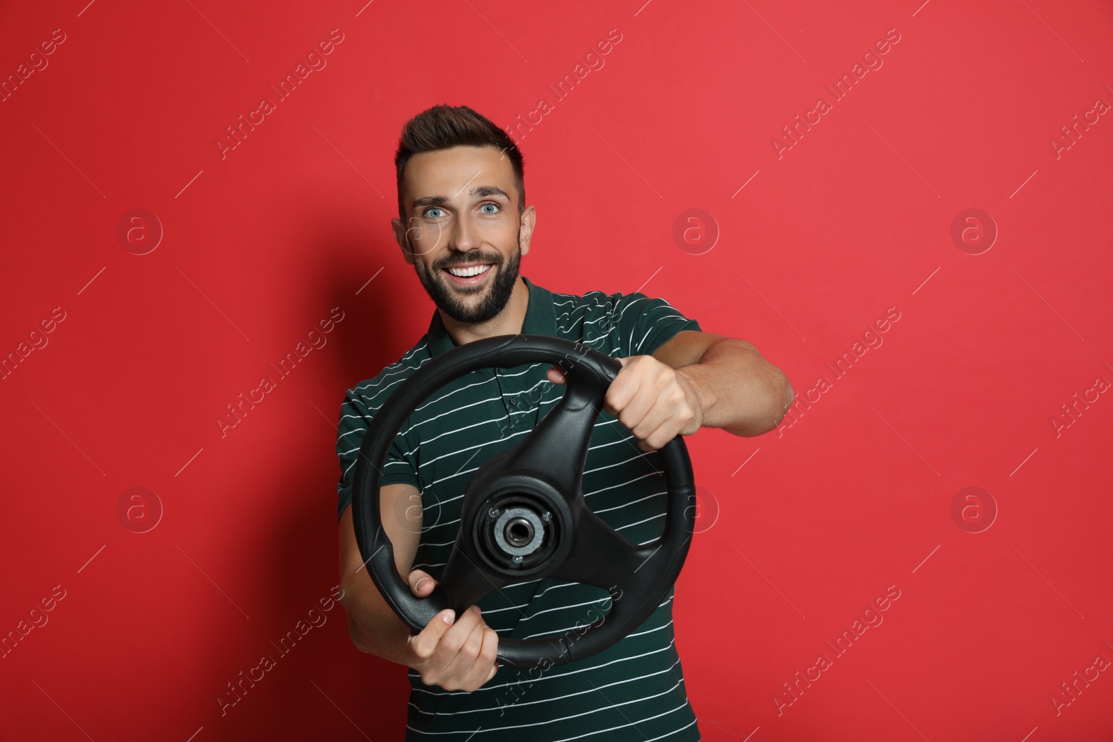 Photo of Happy man with steering wheel on red background