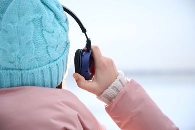 Photo of Young woman listening to music with headphones outdoors, closeup