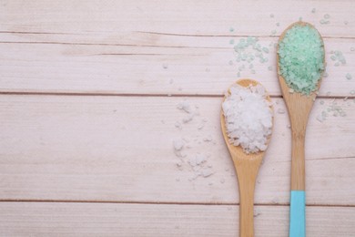 Photo of Spoons with sea salt on white wooden table, flat lay. Space for text