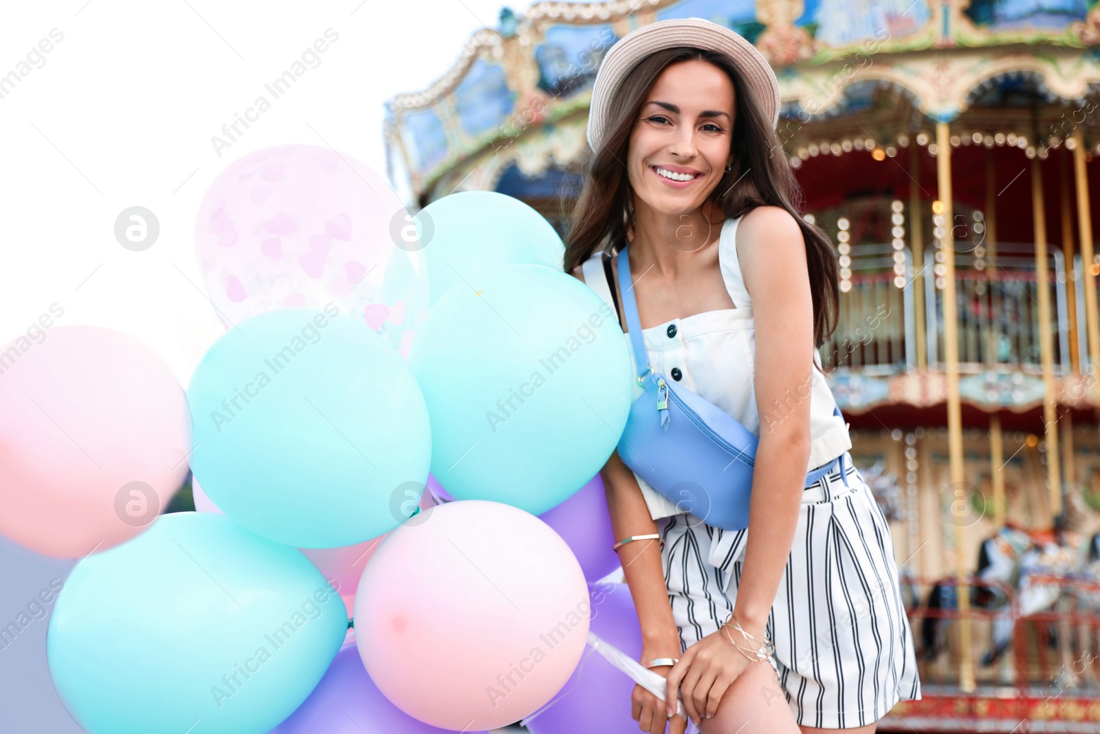 Photo of Attractive young woman with color balloons near carousel