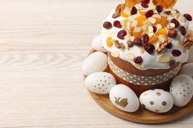 Photo of Traditional Easter cake with dried fruits and decorated eggs on white wooden table, closeup. Space for text