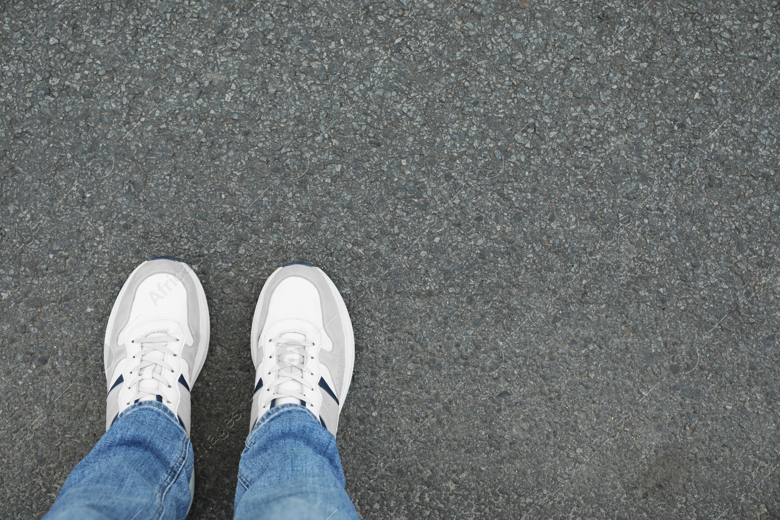 Photo of Man in sneakers standing on asphalt, top view. Space for text