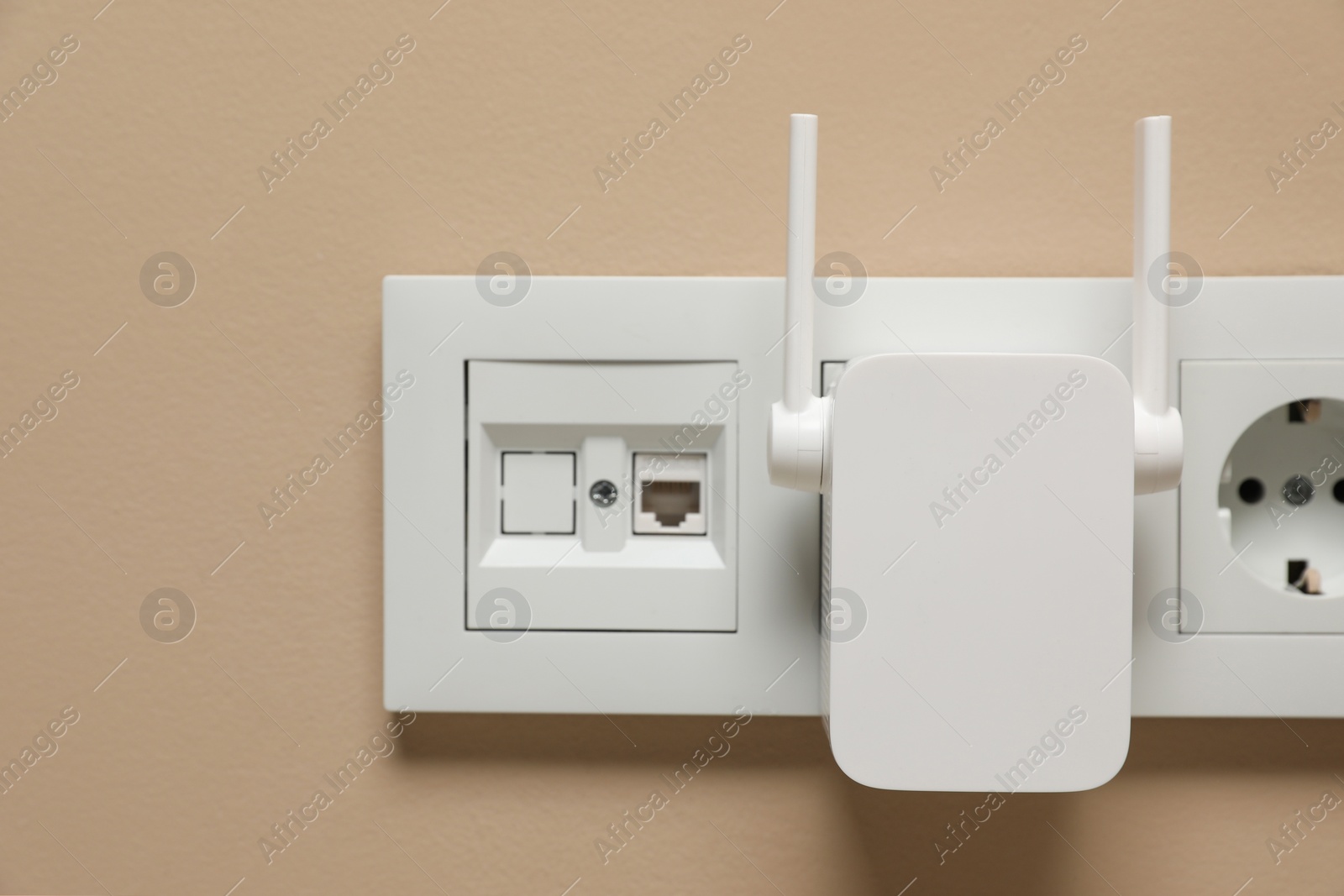 Photo of Wireless Wi-Fi repeater in power socket on beige wall