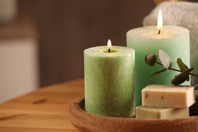 Photo of Spa composition. Burning candles, soap and eucalyptus branch on wooden table, space for text