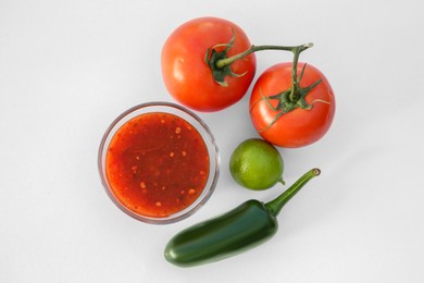 Photo of Bowl with delicious salsa sauce and ingredients on white background, flat lay
