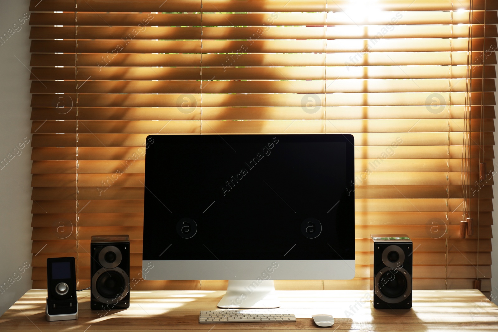 Photo of Modern computer with audio speakers and remote on table indoors