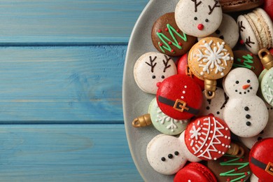 Beautifully decorated Christmas macarons on light blue wooden table, top view. Space for text