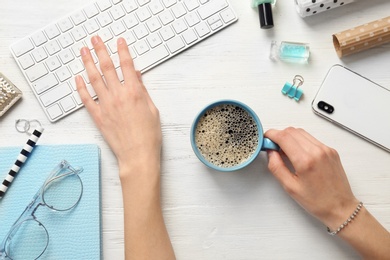 Photo of Blogger with cup of coffee using computer at table, top view