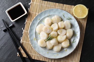 Photo of Raw scallops with lemon, rosemary and soy sauce on dark textured table, flat lay