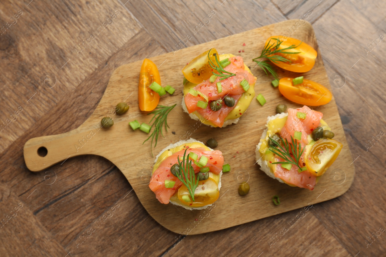 Photo of Tasty canapes with salmon served on wooden table, top view