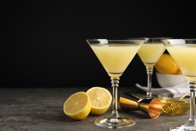 Photo of Delicious bee's knees cocktails and ingredients on grey table against black background, space for text