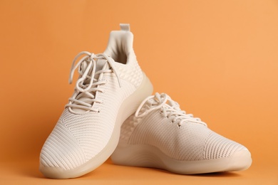 Photo of Pair of stylish sport shoes on orange background, closeup