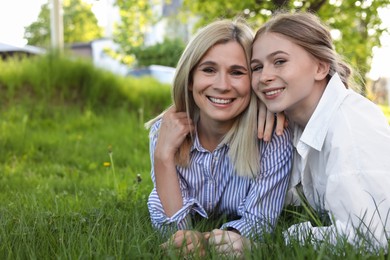 Happy mother with her daughter on green grass in park