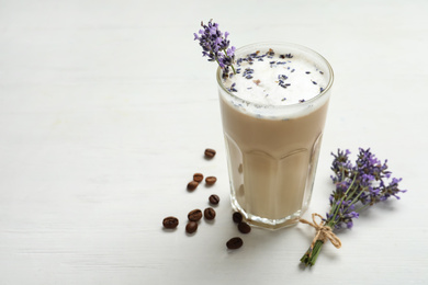 Photo of Delicious coffee with lavender and beans on white wooden table. Space for text