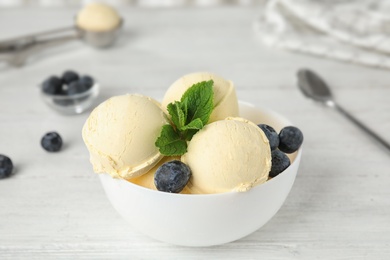 Photo of Delicious vanilla ice cream with blueberries served on wooden table