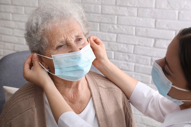 Doctor putting protective mask on senior woman at nursing home