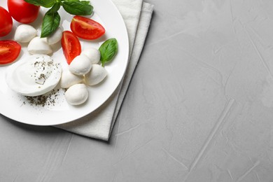 Photo of Delicious mozzarella with tomatoes and basil leaves on light gray table, top view. Space for text
