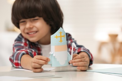 Photo of Cute little boy with paper Saint Nicholas toy at home, focus on hands