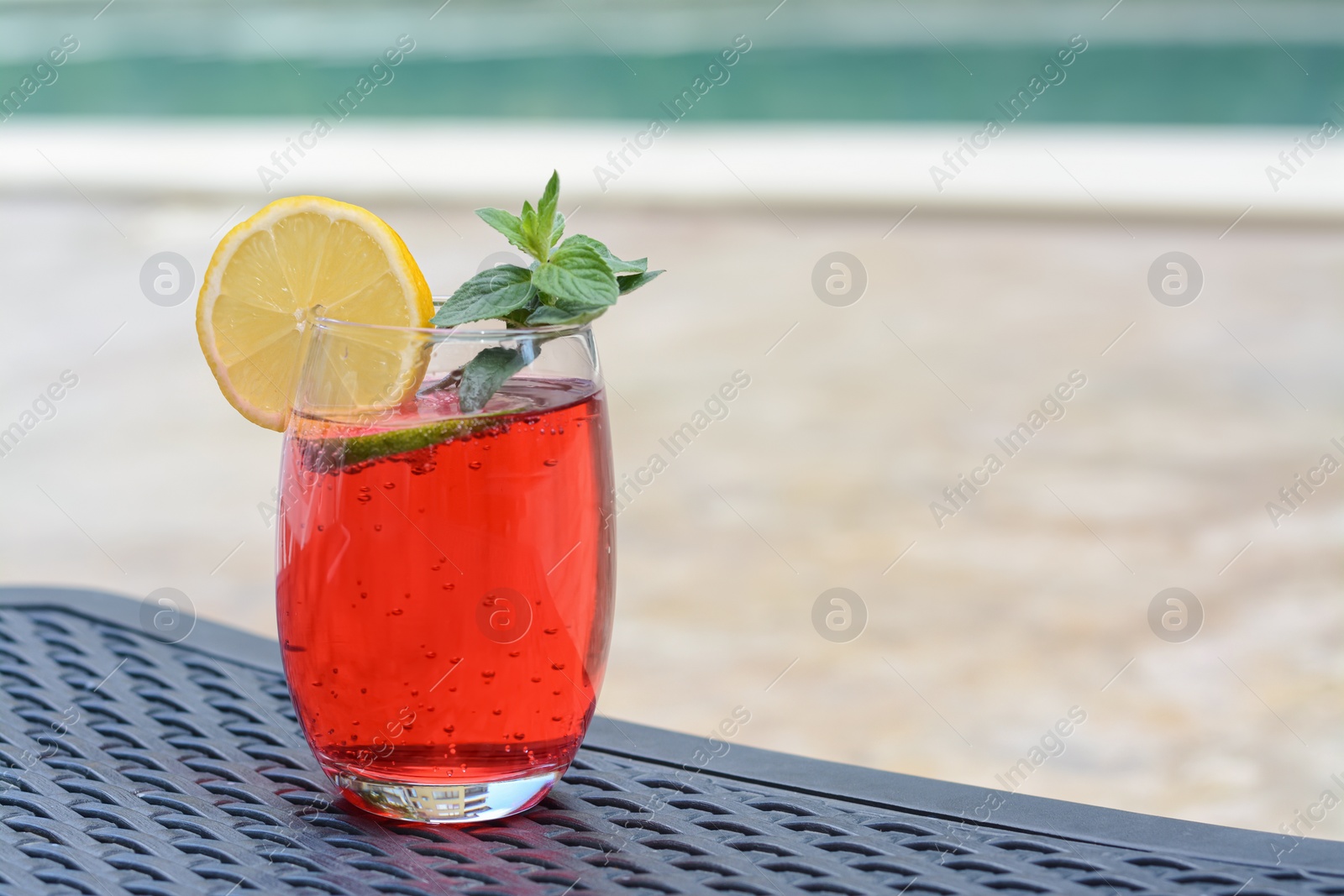 Photo of Glass of delicious cocktail on table outdoors, space for text. Refreshing drink